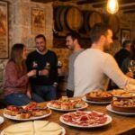 Barra de bar tradicional en el centro de Zamora repleta de tapas variadas, pinchos y vinos con clientes al fondo.
